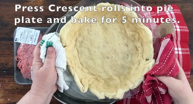 A prebaked crescent roll crust in glass pie plate