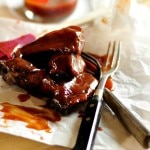 Braised Pork Ribs on parchment paper with sauce and two forks