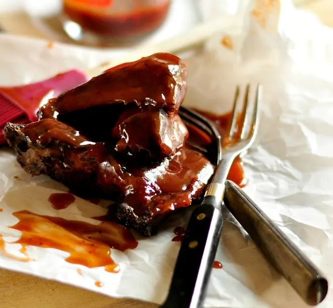 Braised Pork Ribs on parchment paper with sauce and two forks