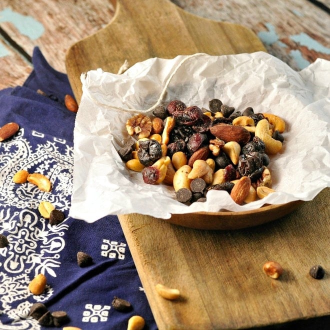 Trail mix wrapped in paper with a bandana and cutting board in background