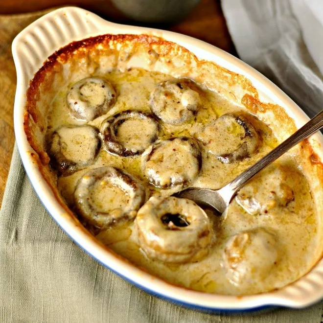 creamy mushrooms in a baking dish with a spoonful being taken out