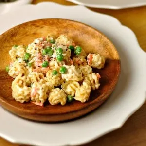 Creamy Ranch Pasta Salad with peas on top in a wooden bowl