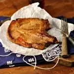 Marinated pork chops on wax paper with two forks and a blue napkin