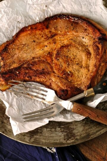 a photo of Marinated Pork chops on a silver plate with two forks