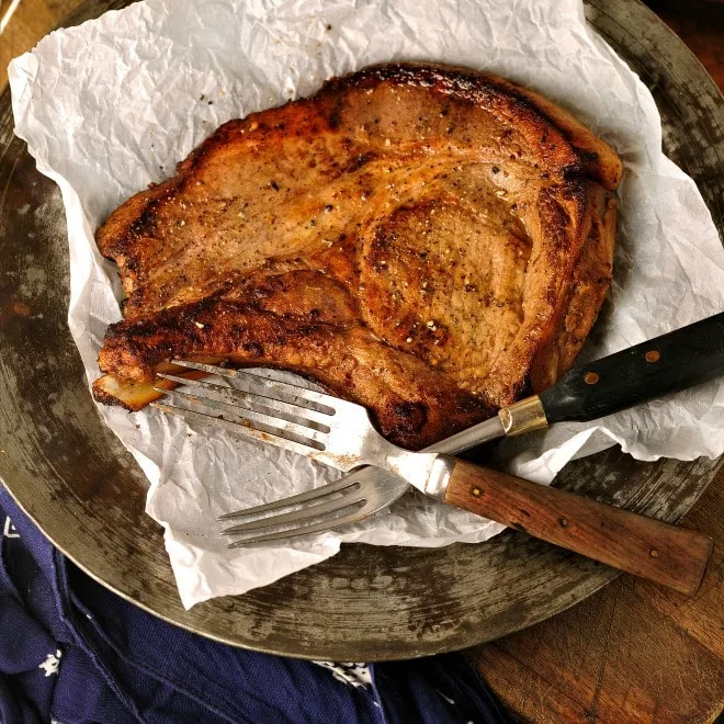 a photo of Marinated Pork chops on a silver plate with two forks