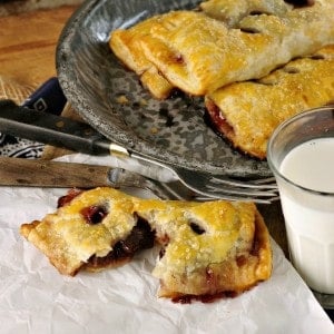 Cherry hand pies split open with a glass of milk and forks