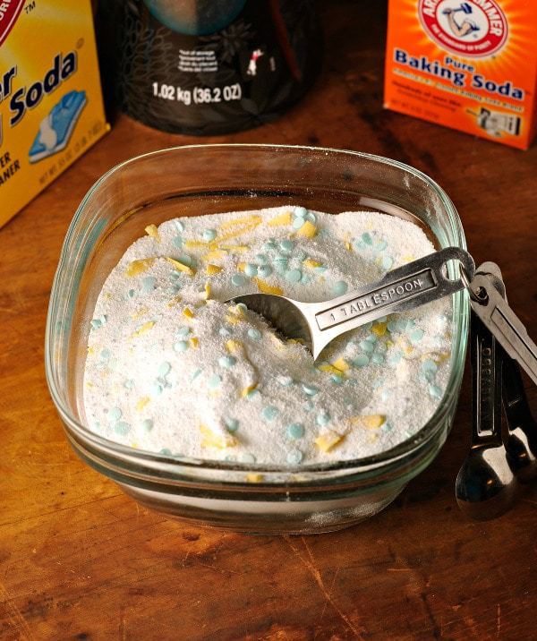 a bowl of homemade laundry soap with measuring spoon and the boxed ingredients