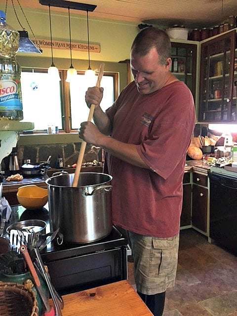 man stirs large stockpot on stove