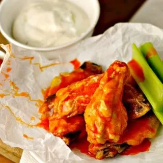 Baked chicken wings with celery and ranch dressing on a white plate