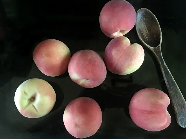 whole fresh peaches with wooden spoon