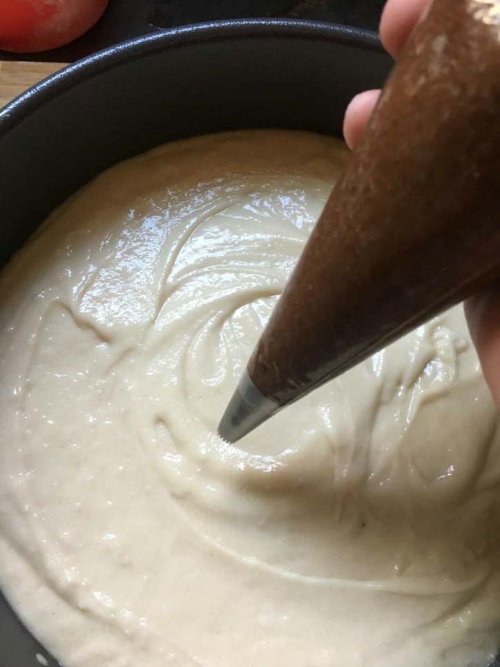 A photo of the start of the piping of the filling for Cinnamon Roll Cake from Scratch