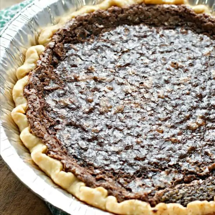 A 45 degree angle shot of the pie showing the shiny upper crust, tin pan and green napkin