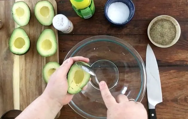 using a spoon to scoop out the avocado meat
