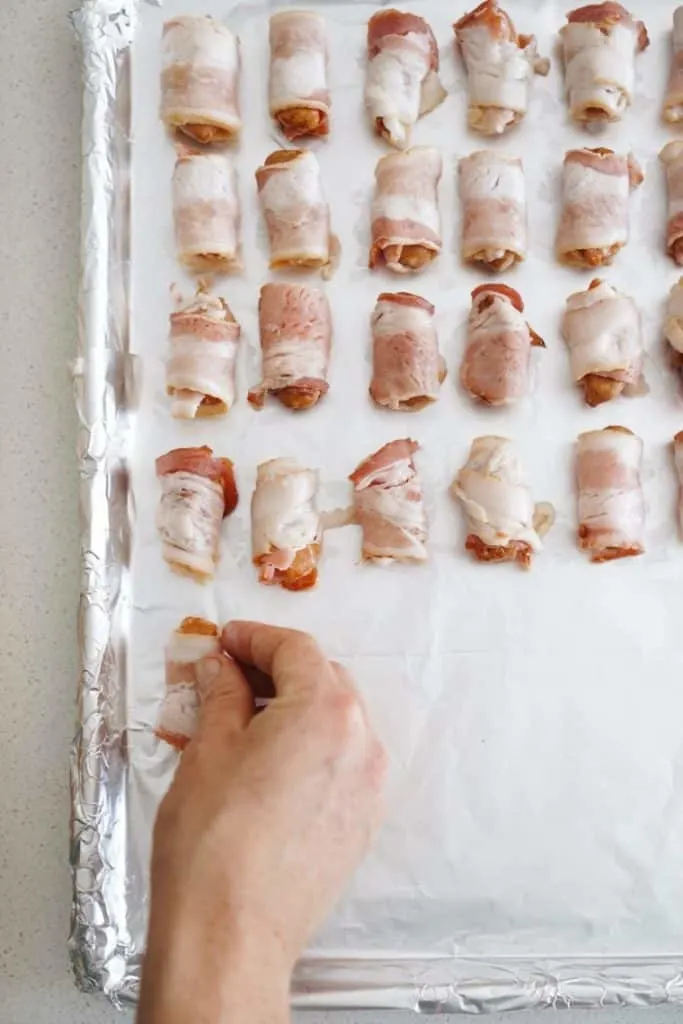 A photo of the bacon wrapped smokies on the baking sheet