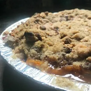 A photo of the baked pie - up close from the side Peach Pie with a Pecan Brown Sugar Crumble