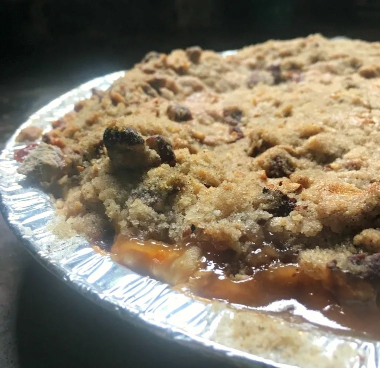 A photo of the baked pie - up close from the side Peach Pie with a Pecan Brown Sugar Crumble