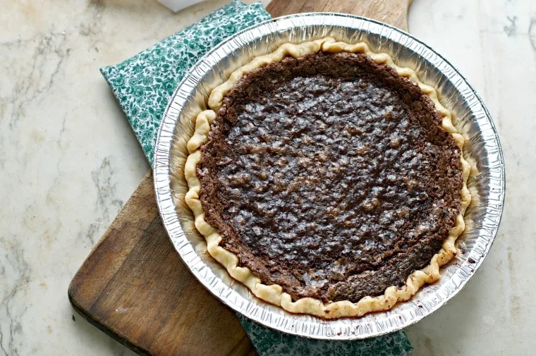 A different overhead shot of the CHOCOLATE CHESS PIE with a cutting board and prairie print napkin beneath
