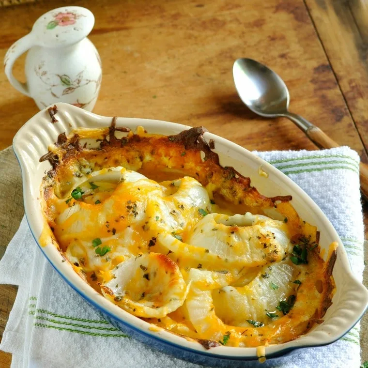 Casserole dish of Tennessee Onions sitting on white towel with spoon and salt shaker in background