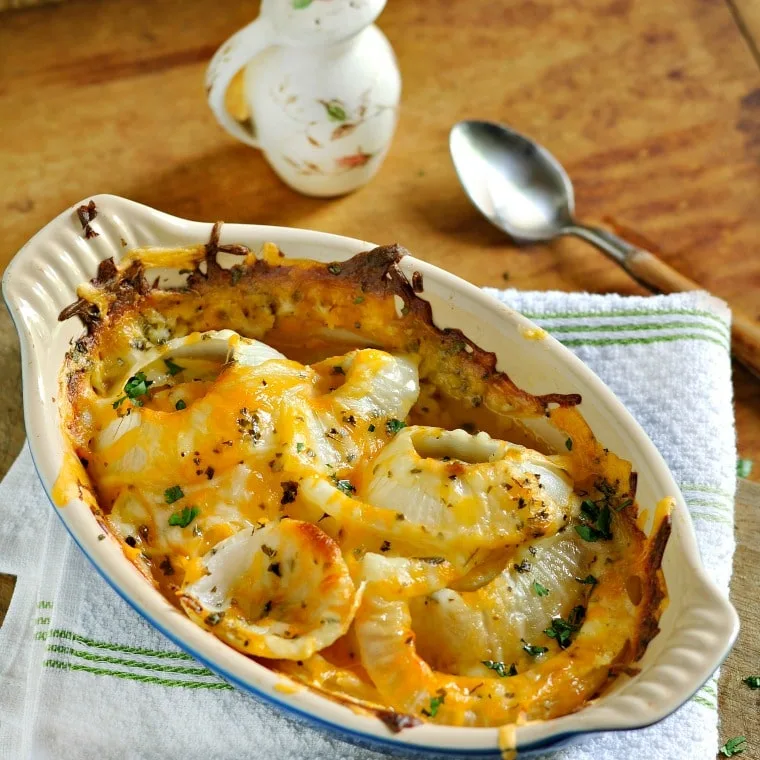 casserole dish of tennessee onions sitting on a green striped towel with a spoon in background