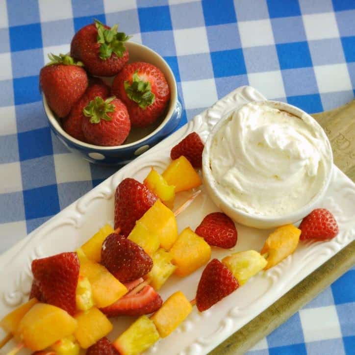 bowl of strawberries and plate of fruit skewers with dip in a bowl