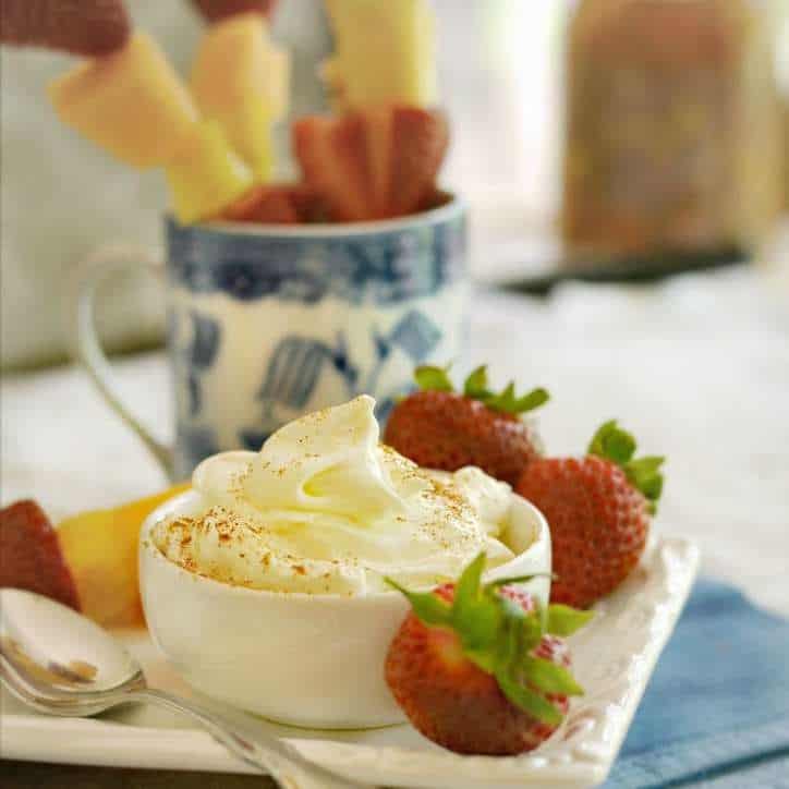 white bowl of fruit dip with strawberries and a spoon