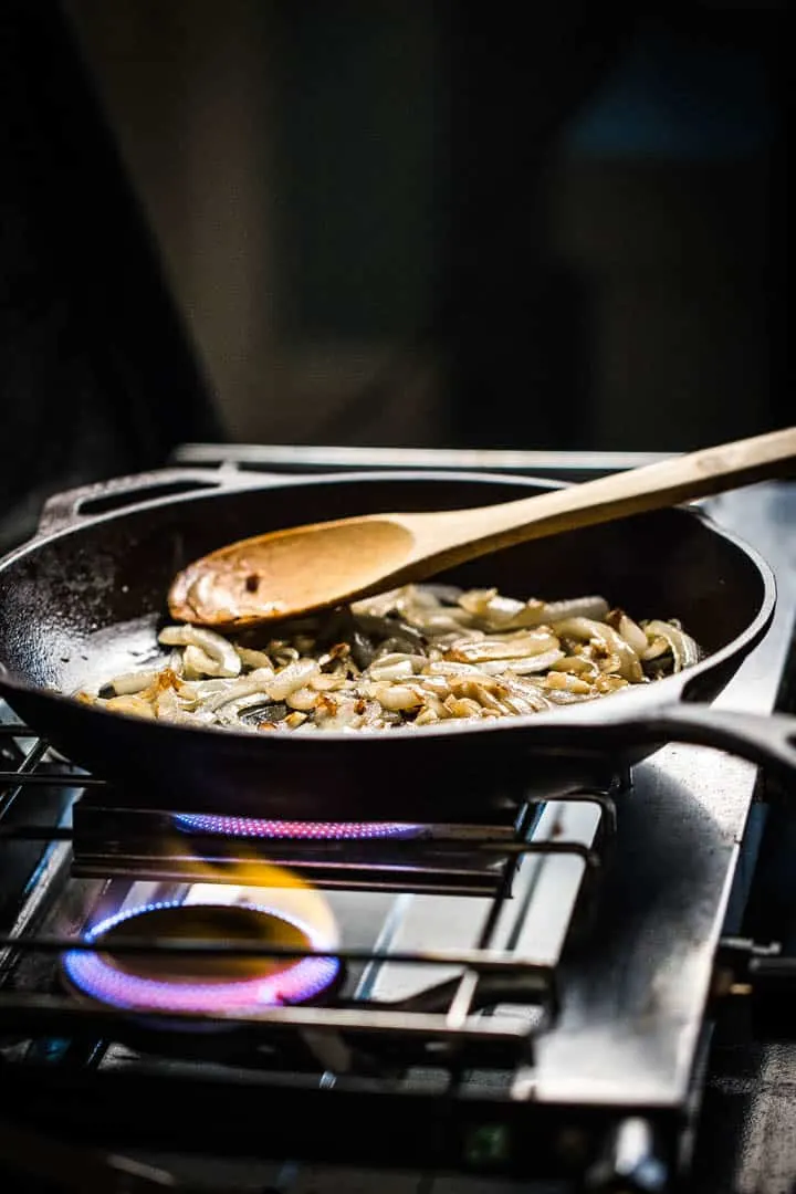 onions and garlic browning in the iron skillet on a gas stove