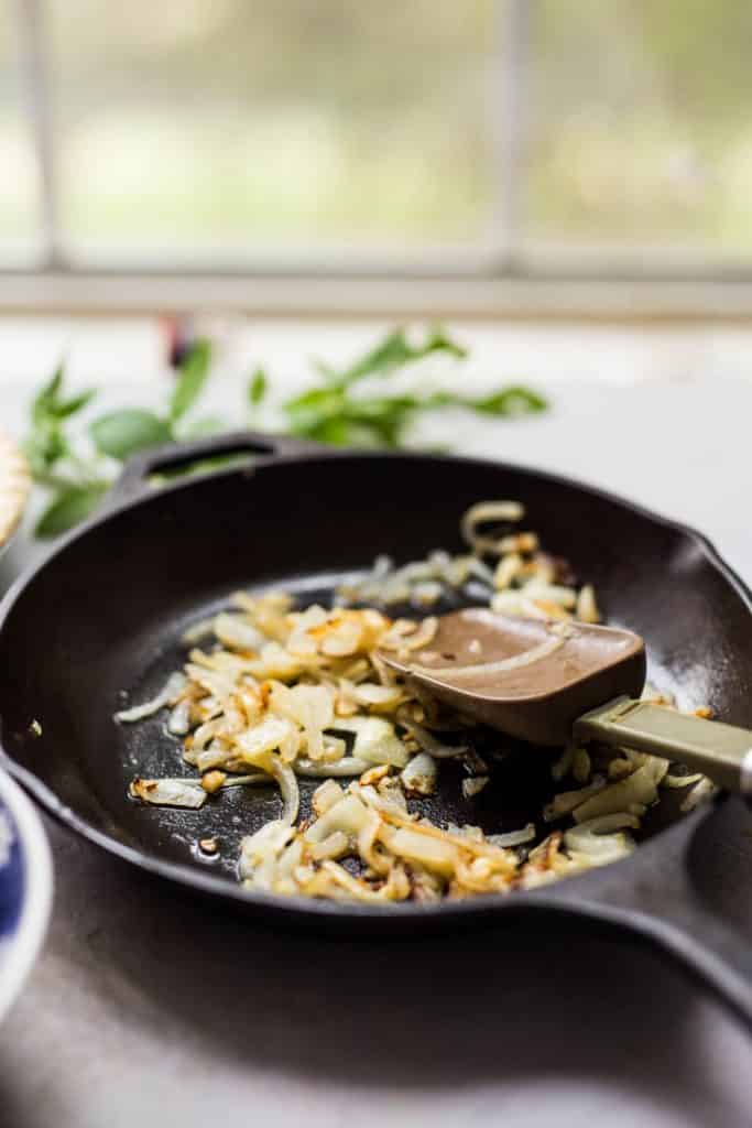 A photo of a frying pan with the onions browning for Tomato Pie