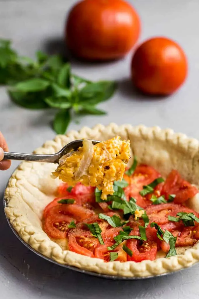 Adding ingredients for tomato pie
