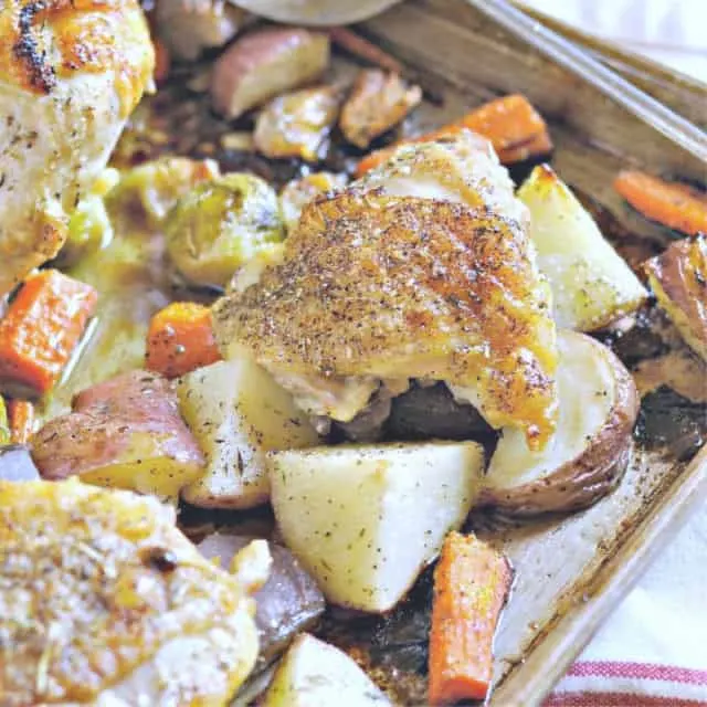 A full bone in chicken thigh in sheet pan with carrots and potatoes