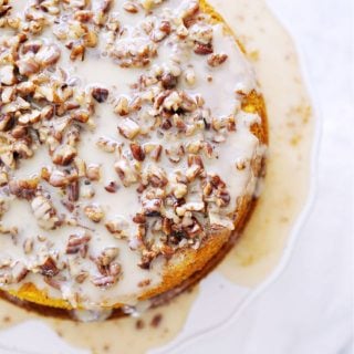 A top down view of the whole pumpkin praline cake with nuts and icing running down the sides and pooling at the bottom