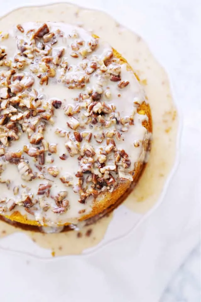 A top down view of the whole pumpkin praline cake with nuts and icing running down the sides and pooling at the bottom