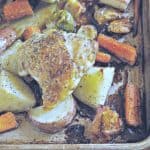 Photo showing crispy Chicken thigh on a sheet pan of potatoes and carrots