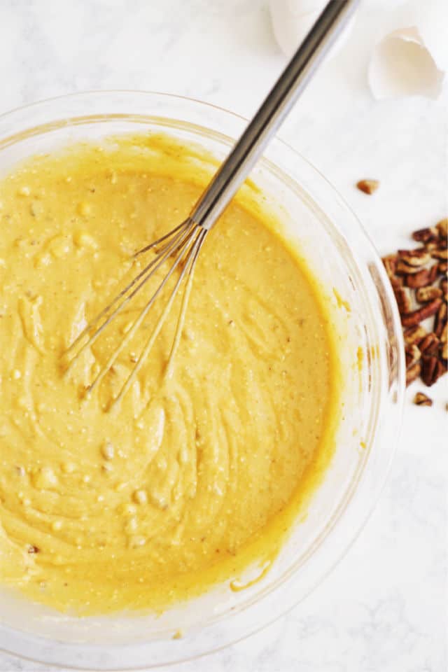 A photo of the bowl of batter for the pumpkin praline cake with pecans at the side of the bowl