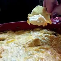 hand using scoop chip to dip up a bite of buffalo chicken dip