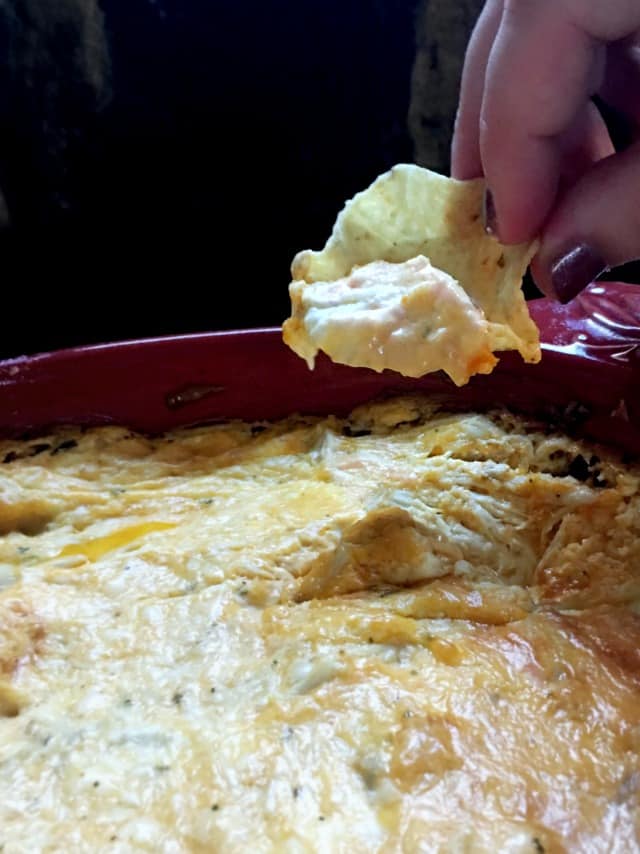 hand using scoop chip to dip up a bite of buffalo chicken dip