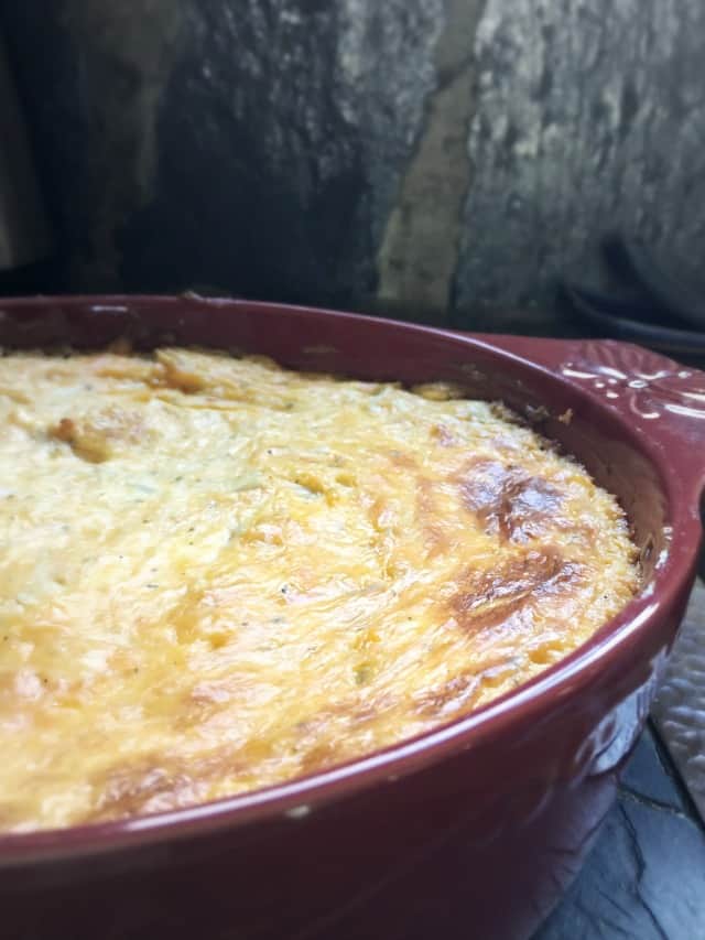 The surface of a red bowl of buffalo chicken dip