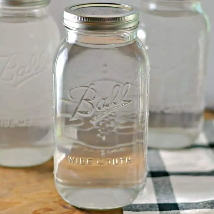 A quart jar with lid that is full of water, black and white towel in background