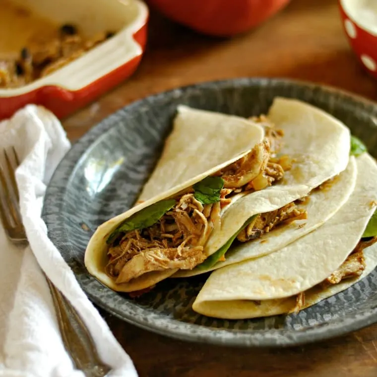gray plate with three fajita tacos a white napkin and fork