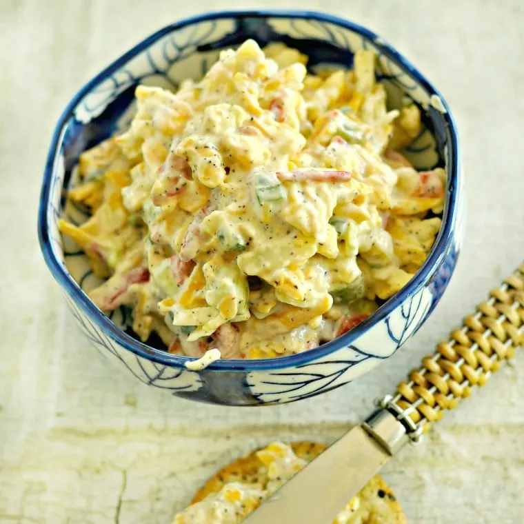 small blue bowl of pimento cheese with spreading knife in background