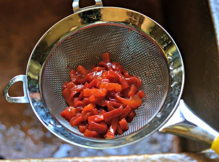 A strainer with chopped pimentos in it