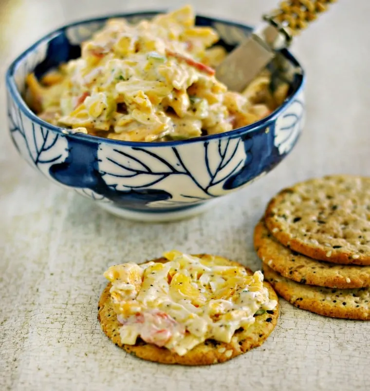 Side view of blue bowl of easy pimento cheese recipe with spreading knife and crackers