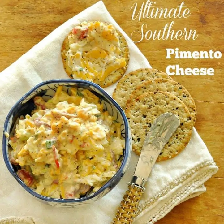 bowl of pimento cheese and 4 crackers one with cheese spread on it, small knife in background