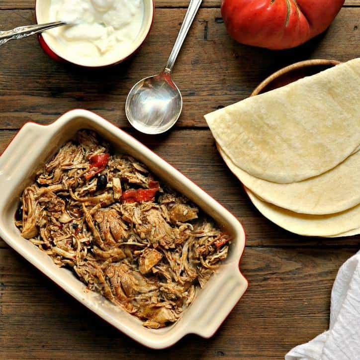 tortilla, sour cream, tomato and chicken fajitas on a wooden table