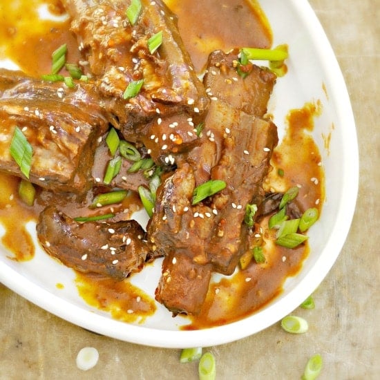 Southern Short Ribs in a white dish with sauce and scallions