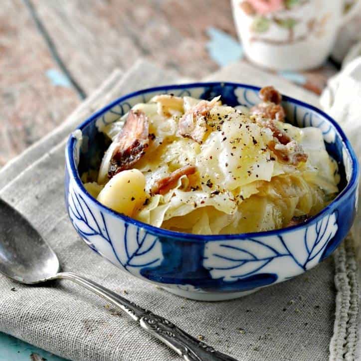 blue bowl filled with southern fried cabbage with spoon and napkin