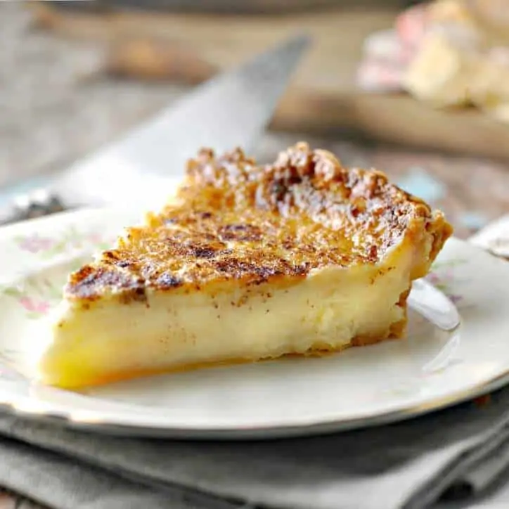 A photo of a slice of Old Fashioned Sugar Cream Pie from the right side on a flowered china plate