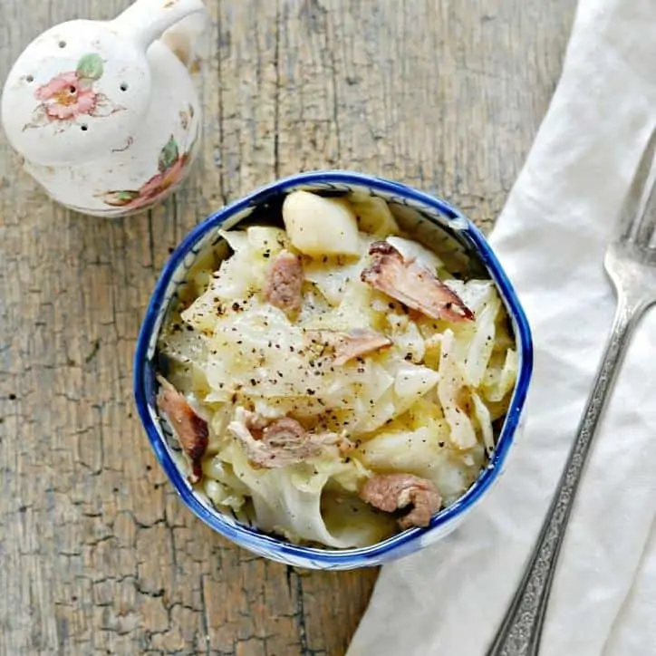 blue bowl of southern fried cabbage recipe on cutting board with fork.