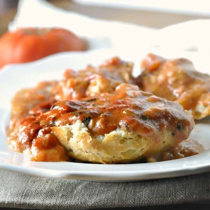 Tomato gravy covering a biscuit on a white plate