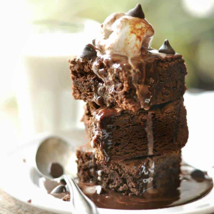 Three brownies stacked up with chocolate syrup and ice cream