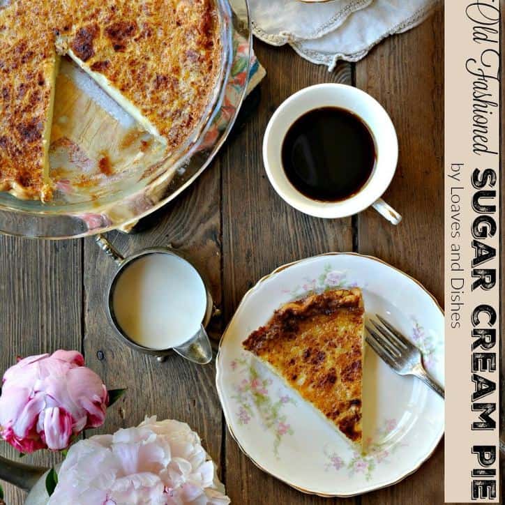 A photo from above of a place setting of a whole sugar cream pie, a slice of pie, a cup of coffee, a creamer and a peonie